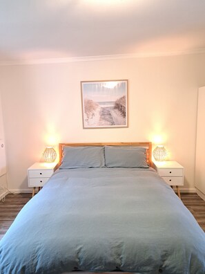 A bedroom with a bed, two bedside tables with lamps, a framed picture on the wall, and a wooden headboard. - Oceanviews-Walk to Goolwa Beach-Linen-Pet Friendly! (Goolwa Beach)