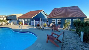 Ein Wohnhaus mit Swimmingpool, zwei Häuser mit roten Dächern und einem weißen Zaun.