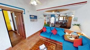 A living room with a blue sofa, red cushions, a wooden coffee table, and a lamp.
