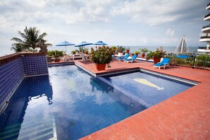 A pool area with blue-tiled walls, lounge chairs, and umbrellas.