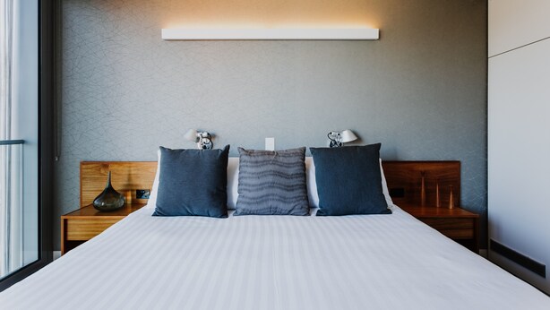 A modern hotel room with a large bed, two bedside tables, and a nightstand.