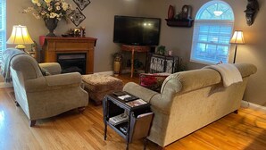Un salon avec une cheminée, un téléviseur et une grande fenêtre.