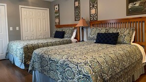 Une chambre avec deux lits, un ventilateur de plafond et des œuvres d’art décoratives au mur.