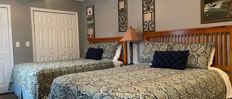 A bedroom with two beds, a ceiling fan, and decorative wall art.