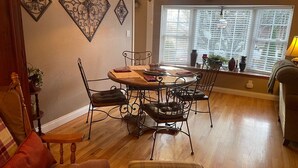 Un coin repas avec une table ronde, quatre chaises et une fenêtre équipée de stores.