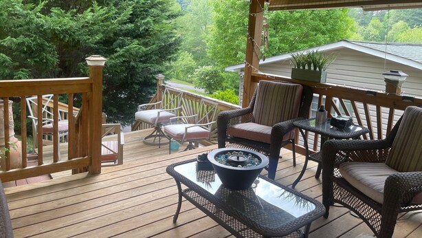 Une terrasse en bois avec des meubles en osier, une table en verre et une plante en pot.