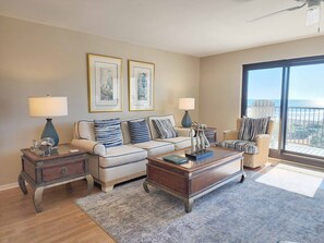 Ein Wohnzimmer mit einer Couch, zwei Beistelltischen, einem Couchtisch und Blick auf den Ozean.