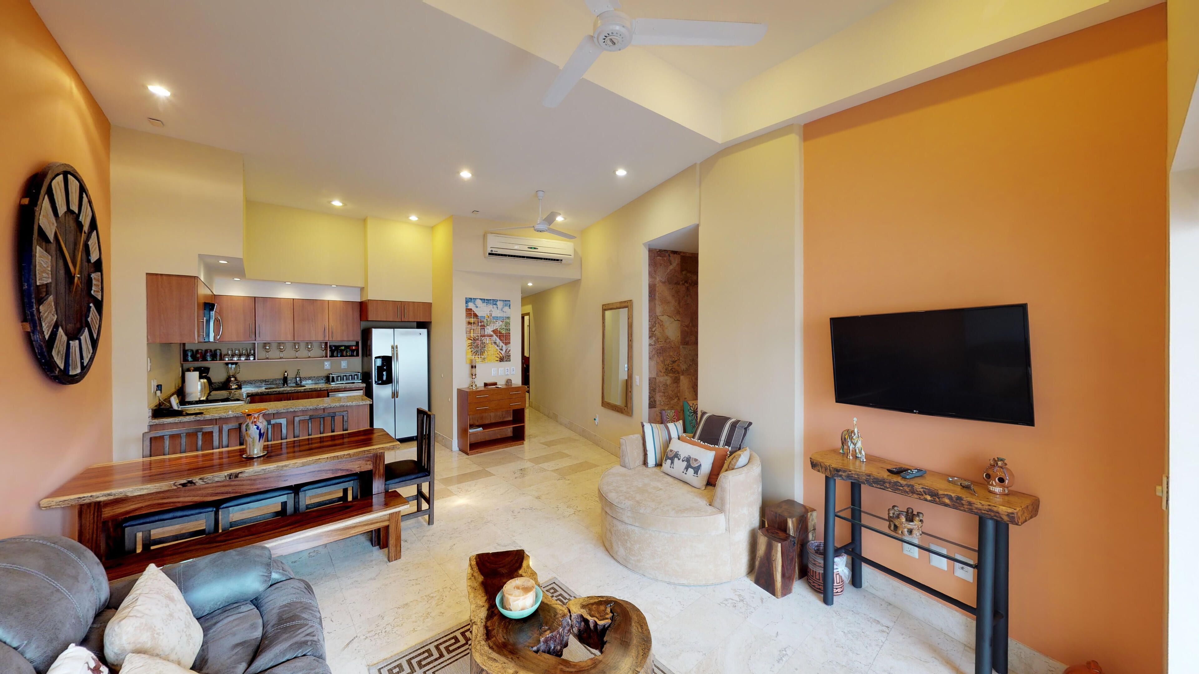 Una sala de estar moderna con un sofá, una mesa de centro y un televisor montado en la pared.