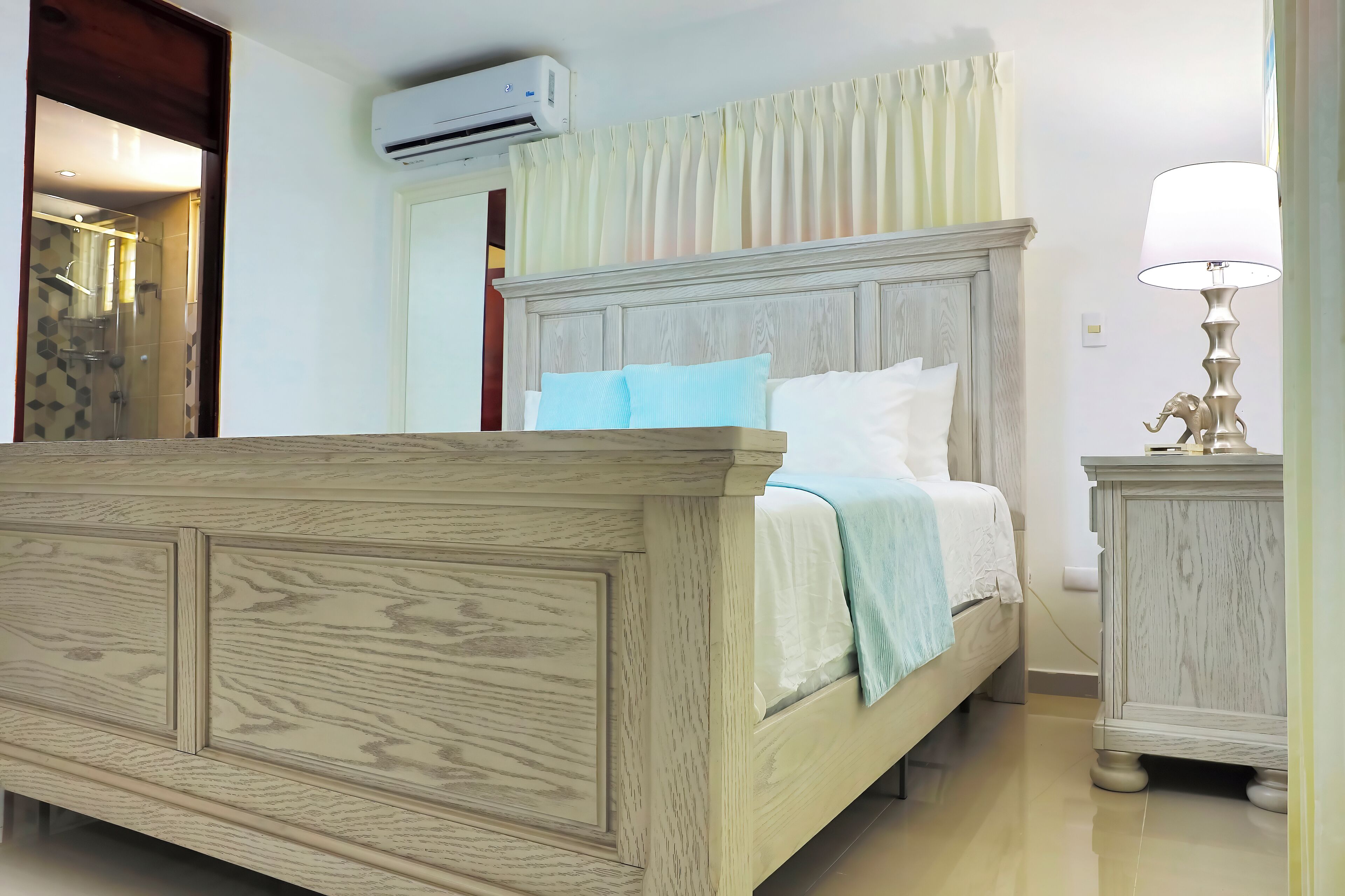 Un dormitorio con una cama de madera, una mesita de noche con lámpara y un equipo de aire acondicionado.