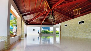 Un intérieur spacieux avec un plafond haut, un plancher ciré et une vue sur la verdure environnante.