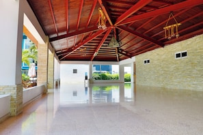 Un intérieur spacieux avec un plafond haut, un plancher ciré et une vue sur la verdure environnante.