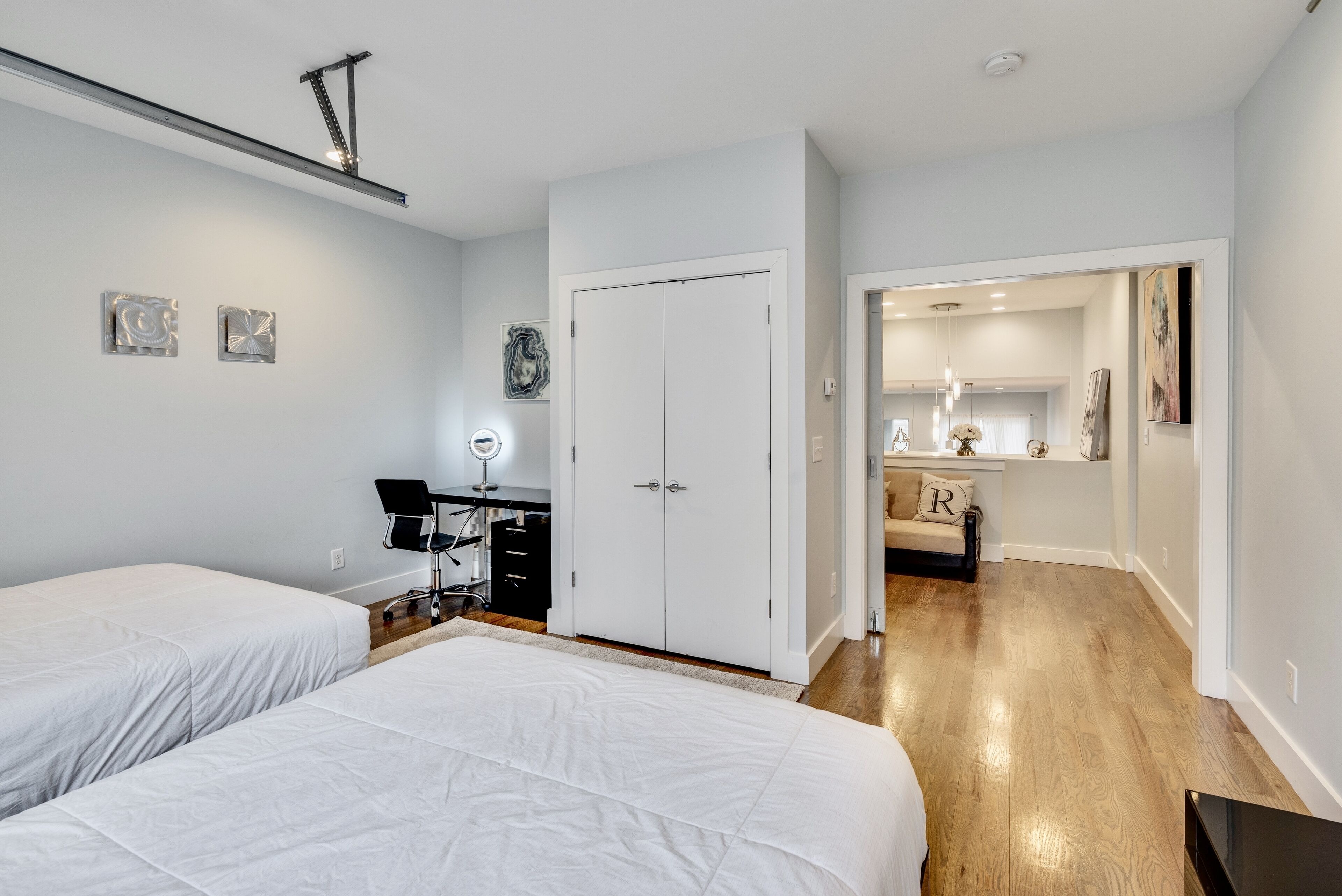 Een slaapkamer met twee bedden, een bureau met stoel, een kledingkast en een badkamer die door een open deur zichtbaar is.