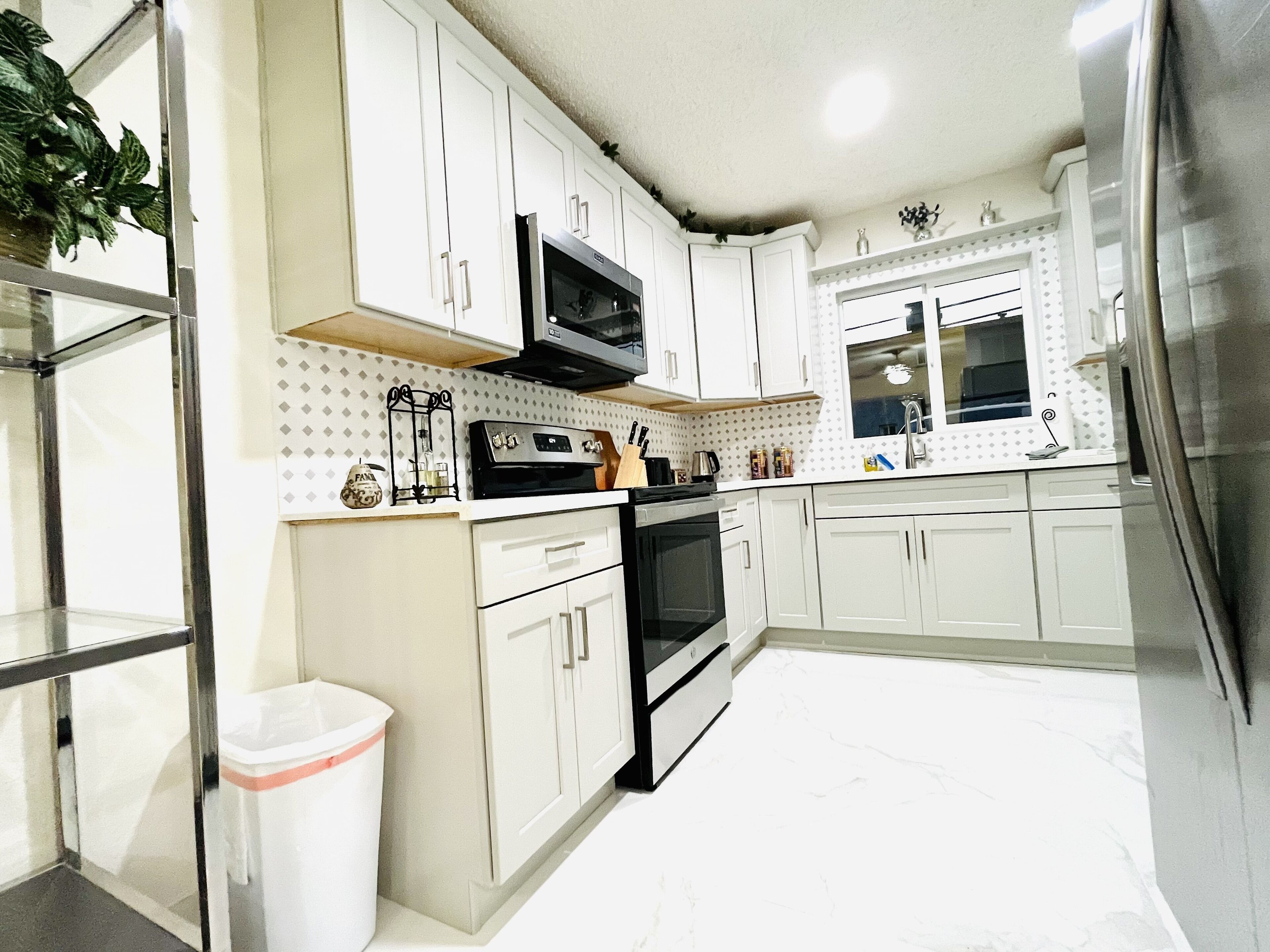 A modern kitchen with white cabinets, a stainless steel refrigerator, and a microwave.
