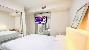 Een hotelkamer met een groot bed, een aan de muur bevestigde televisie en een nachtkastje.
