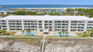 Ein mehrstöckiges Hotel mit Pool und Blick auf den Strand.