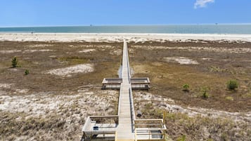 Une promenade en bois menant à des cabanes de plage, d’où l’on a une vue dégagée sur l’océan.