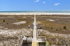 A wooden boardwalk leading to beach huts with a clear view of the ocean.