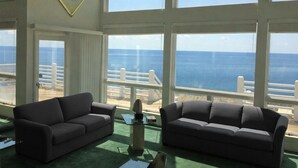 A room with two dark sofas facing a large window overlooking the sea. - SOUND FRONT / Kite-in/out Direct Beachfront Access Sunsets Best Kiteboard Spot (Rodanthe)
