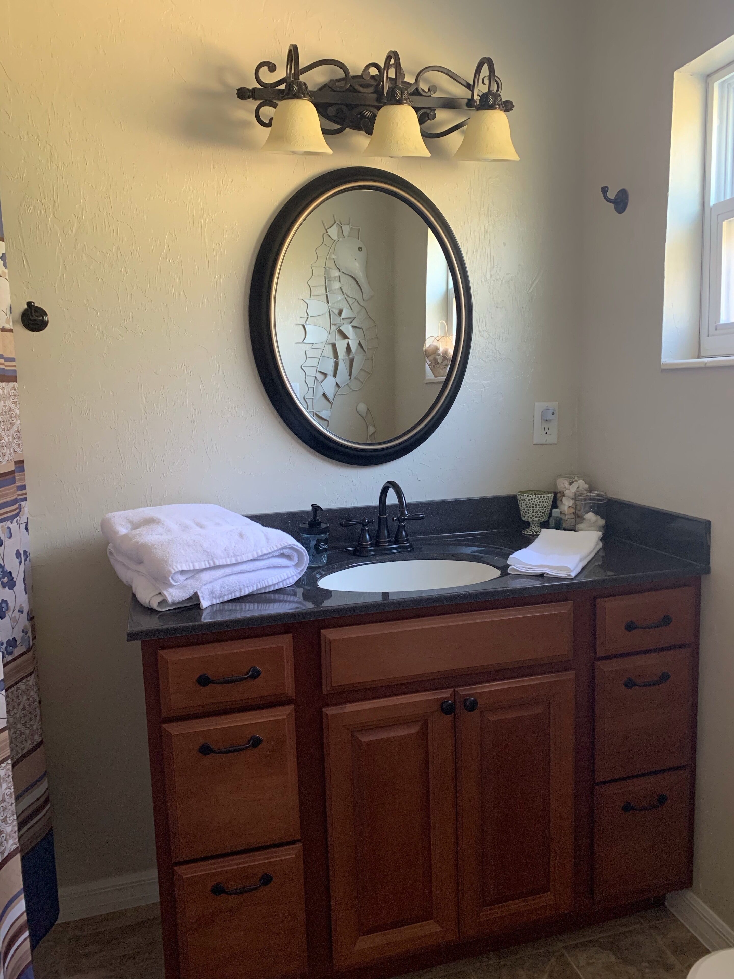 A bathroom with a wooden vanity, a round mirror, and a sink.