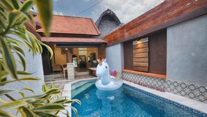 A swimming pool with a unicorn decoration, a thatched roof building, and a tiled exterior wall. - Krishna Villas (Legian)