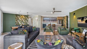 A modern living room with a sofa set, a coffee table, and a dining area with a kitchen in the background.