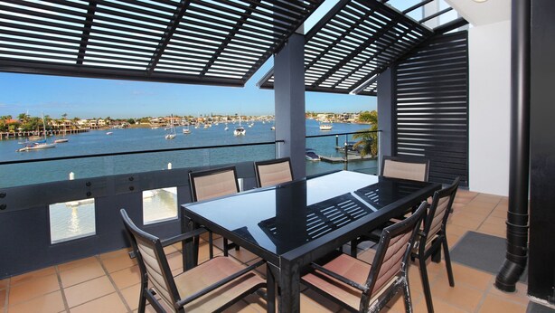 Une terrasse avec une table et des chaises donnant sur une marina où sont amarrés des bateaux.