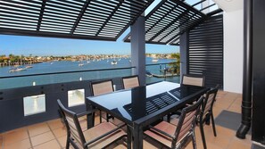 A terrace with a table and chairs overlooking a marina with boats. - Kirribilli 13 - Two Bedroom Apartment with River View! (Mooloolaba)