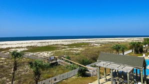 Uitzicht op een strand met een houten terras, een prieel en een zwembad.
