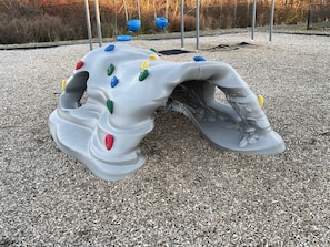 A playground structure with climbing holds and a slide.