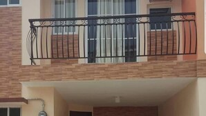 A two-story residential building with a balcony on the upper floor, a small entrance area, and a visible air conditioning unit. - 2 storey townhouse 3 Bedrooms in CEBU FOR RENT - ENTIRE GUEST HOUSE. (Talisay City)