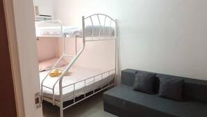 A bunk bed with a lower bunk, a bedside table, and a grey sofa with cushions. - 2 storey townhouse 3 Bedrooms in CEBU FOR RENT - ENTIRE GUEST HOUSE. (Talisay City)