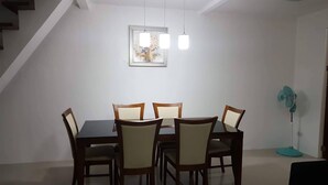 A dining area with a table and chairs, a framed picture on the wall, and a standing fan. - 2 storey townhouse 3 Bedrooms in CEBU FOR RENT - ENTIRE GUEST HOUSE. (Talisay City)