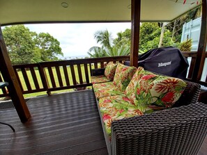 A covered outdoor seating area with a wicker sofa and a black grill cover labeled "Masport". - Capture the view, hear the waves -TepaeruVista (Vaimaanga)