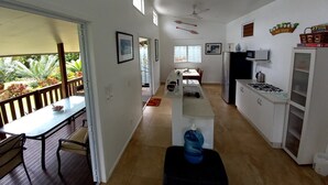 A spacious kitchen with a dining area, a water dispenser, and a refrigerator. - Capture the view, hear the waves -TepaeruVista (Vaimaanga)