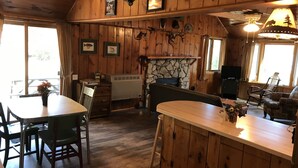 Ein Holzblockhaus-Interieur mit Essbereich, Kamin und Steinwand.