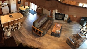 Ein gemütliches Blockhaus-Interieur mit Essbereich, einer Couch, einem Kamin und einer Küche.