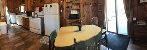 Una cocina con armarios de madera, un refrigerador, una estufa, un microondas y una mesa de comedor con sillas.