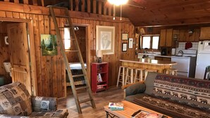 Ein gemütliches Blockhaus-Interieur mit Holzausstattung, einem Essbereich und einer Küche.