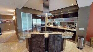 Una cocina moderna con una isla central, electrodomésticos de acero inoxidable y armarios oscuros.