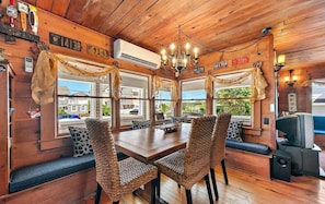 Enjoy meals in a warm and inviting dining area with a large table, woven chairs, and a chandelier.