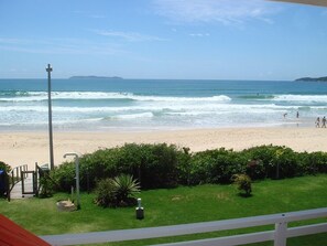 Blick auf einen Strand mit blauem Himmel, feinem Sand und ein paar Spaziergängern.