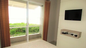 A bedroom with a bed, a TV mounted on the wall, and a power outlet. - 3 SEA-FRONTED Houses - Beach of Mariscal, Bombinhas, SC - HOUSE #2 (Canto Grande)