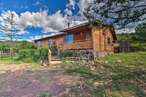 A rustic cabin with a wooden exterior, a stone foundation, and a wooden porch. - Peaceful Ranch Cabin, 3 Mi to Becker Lake! (Springerville)