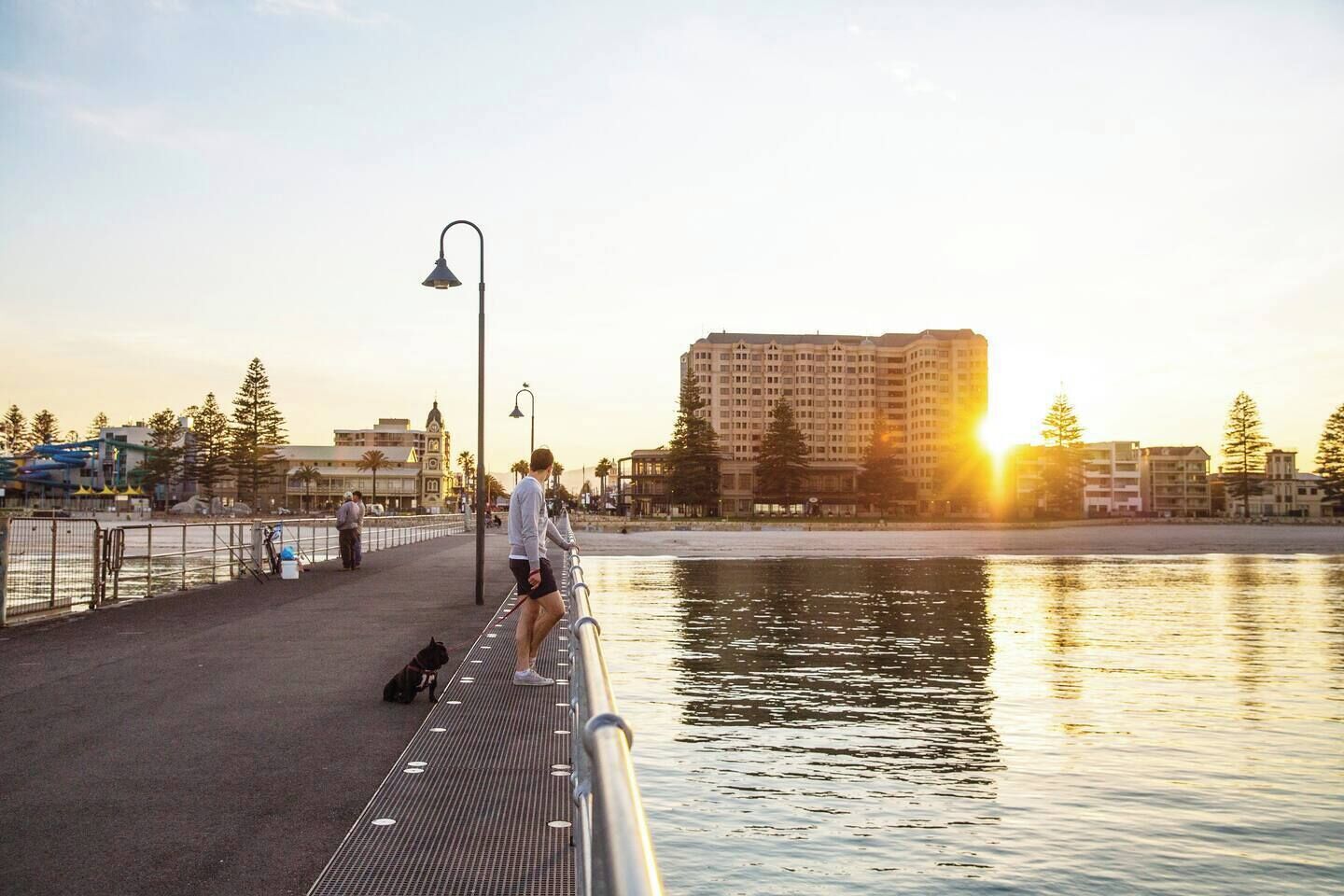 A waterfront promenade with a pedestrian walkway, a lamppost, and a large building in the background.
