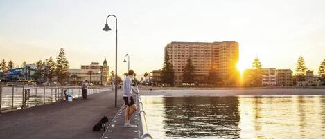 A waterfront promenade with a pedestrian walkway, a lamppost, and a large building in the background.