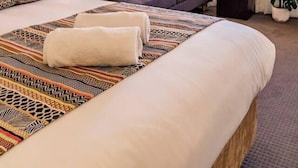 Une chambre d’hôtel avec un lit, un canapé, une lampe, une plante et une fenêtre avec des rideaux.