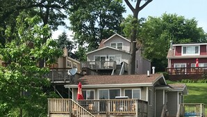 A two-story house with a wooden deck and a staircase leading to the upper floor.