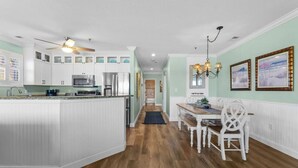 A kitchen with white cabinets, a central island, and a dining area with white chairs.