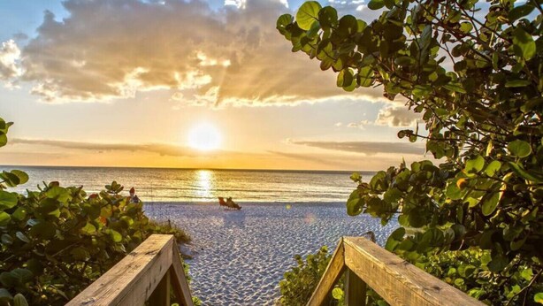 A wooden staircase leading to a beach with a sunset in the background.