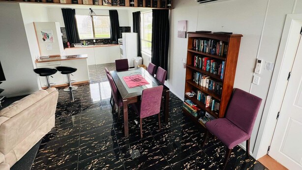 A modern living space with a dining area, kitchen, and a bookshelf. - Our house is the perfect holiday home (Raetihi)